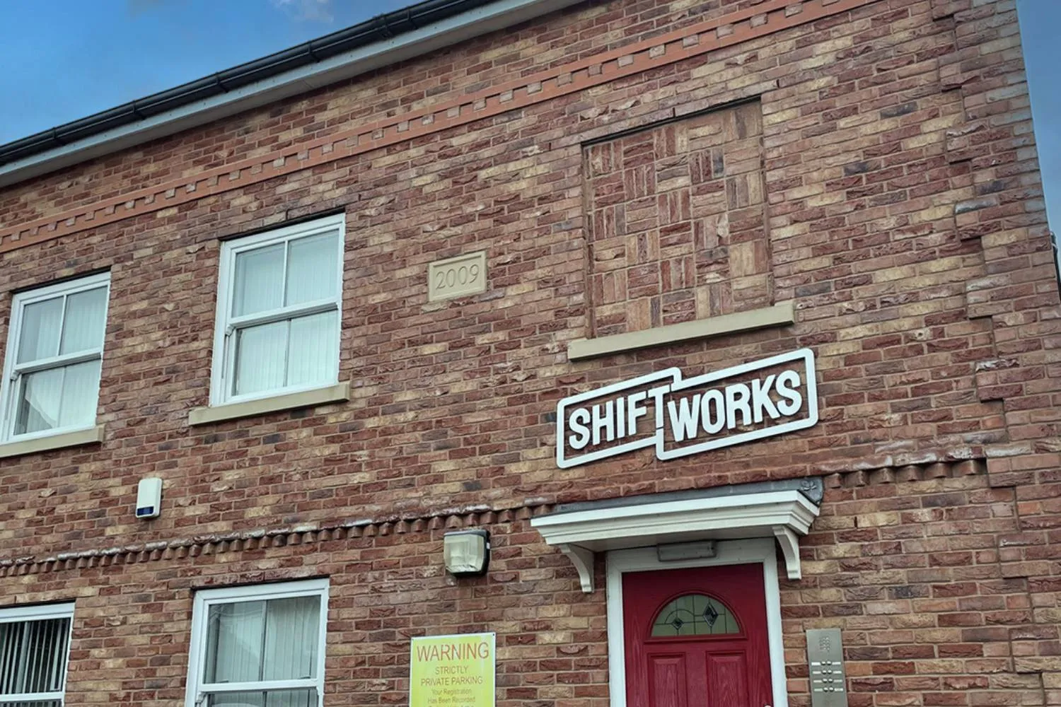 The red front door and ShiftWorks sign at Lake House, Hoylake